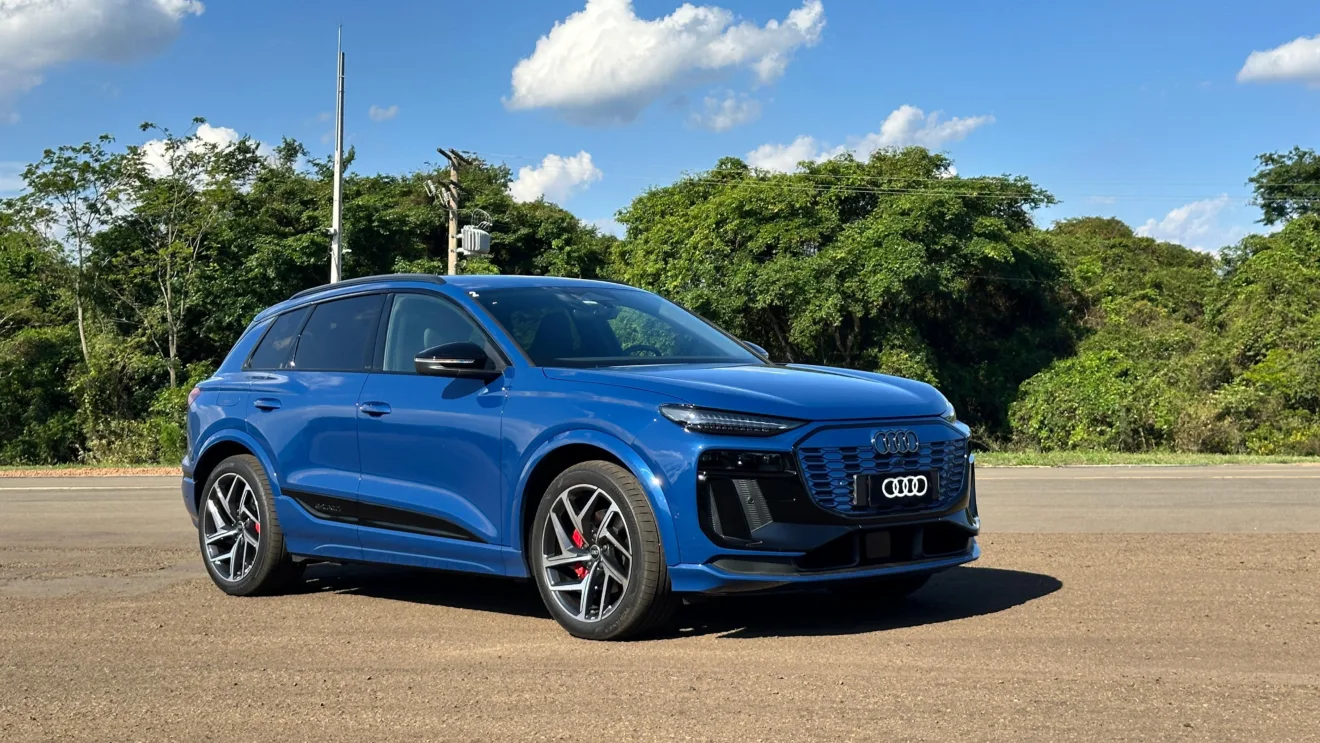 Audi Q6 e-tron azul parado de frente no asfalto com árvores ao fundo