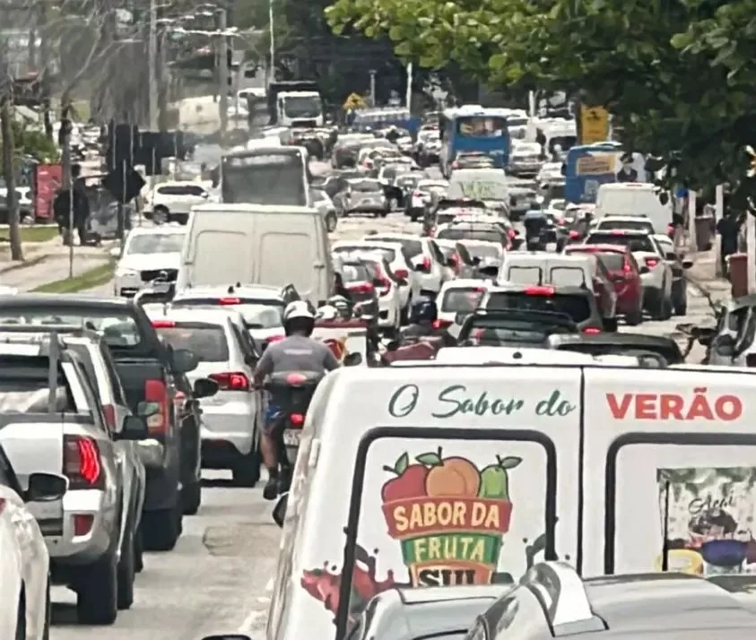 Trânsito de carros na SC-404 com diversos modelos diferentes e vistos de trás