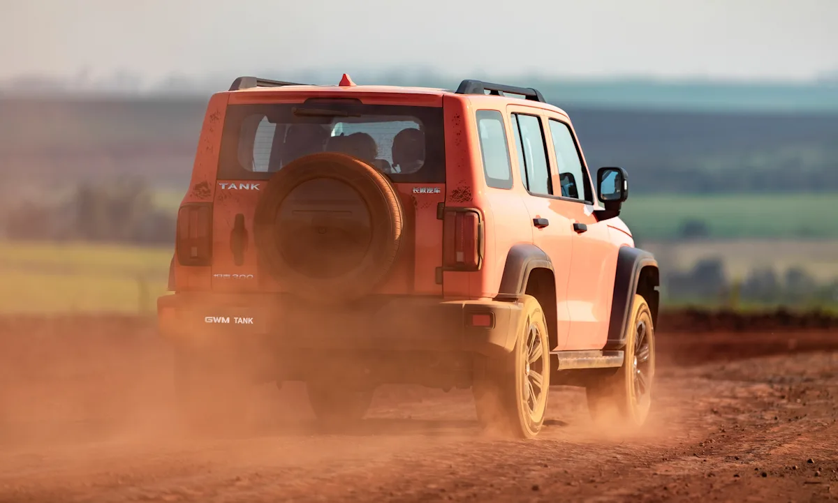 GMW Tank 300. Carro em ambiente off-road com poeira. Imagem da traseira.