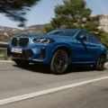 SUV BMW X4 xDrive20i M Sport azul andando na estrada e no asfalto com árvores ao fundo