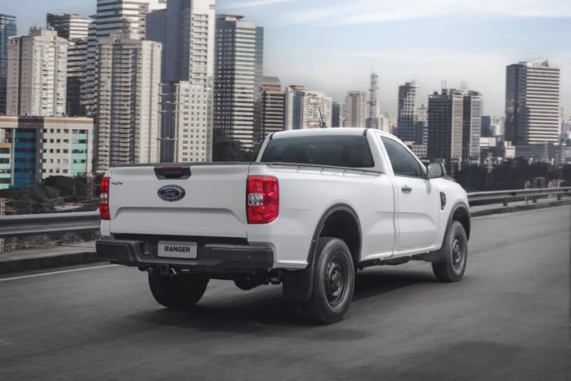 Ford Ranger com duas portas andando na cidade sobre o asfalto com prédios ao fundo