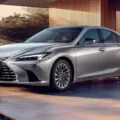 Lexus ES prata, visto de frente e com uma casa de fundo