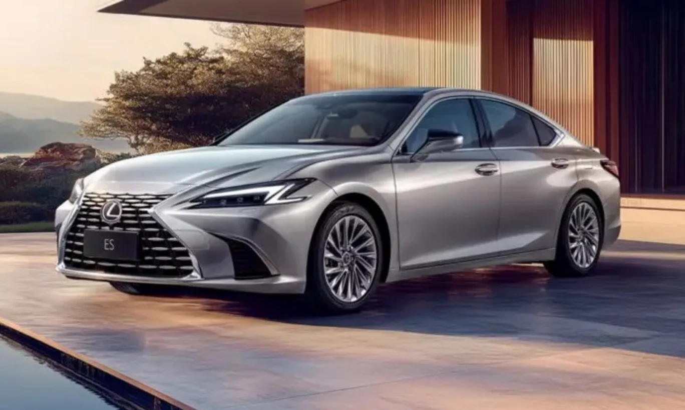 Lexus ES prata, visto de frente e com uma casa de fundo