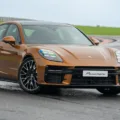 Porsche Panamera 2025 dourado de frente parado em uma pista molhada