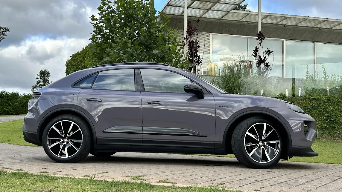 Porsche Macan 4 roxo de lateral com as rodas dianteiras esterçadas e casa ao fundo