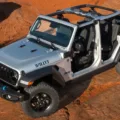 Jeep Wrangler Willys 4xe prata com detlahes em preto parado no alto da montanha