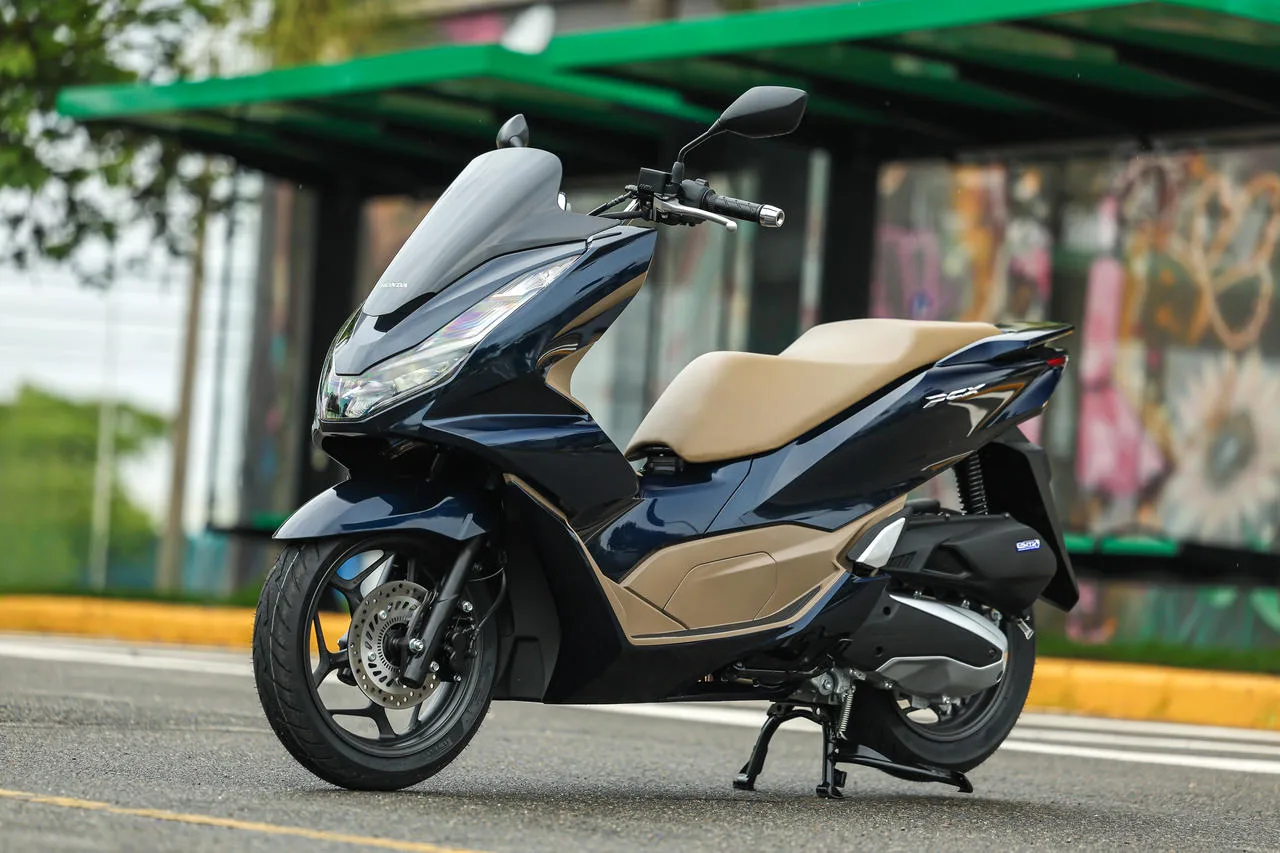 Honda PCX 160 2025 em foto parada no asfalro com ponto de ônibus ao fundo