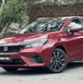 Honda City Hatch Touring 2025 vermelho de dianteira estacionado em frente a um portão branco