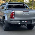 Toyota Hilux SRX Plus prata parada de traseira em um estacionamento com uma floresta ao fundo