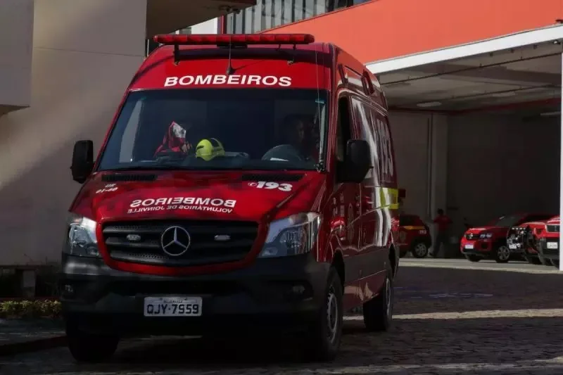 Ambulância vermelha dos bombeiros, vista de frente e com quartel ao fundo