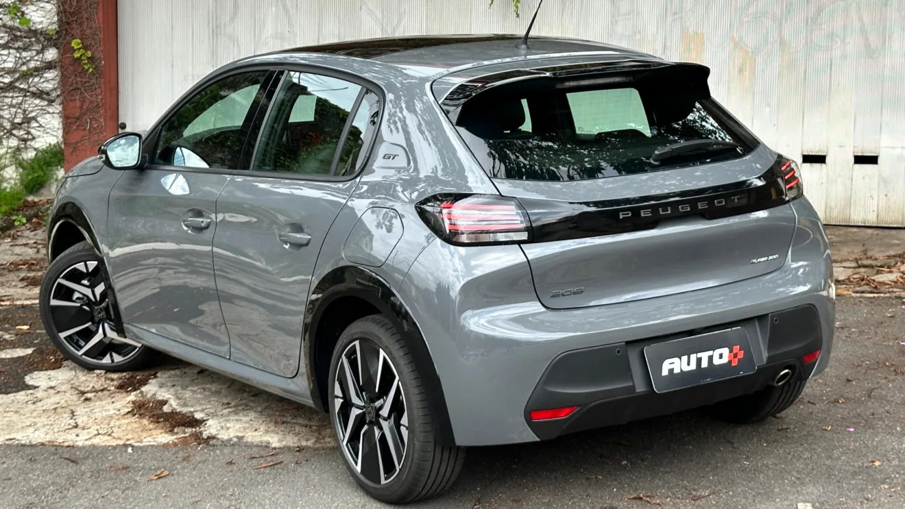 Peugeot 208 GT 2025 cinza parado de traseira visto do alto com portão branco ao fundo