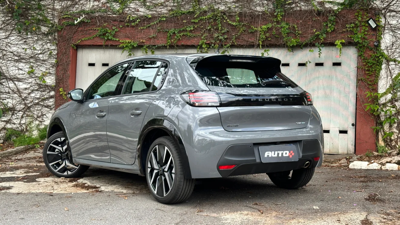 Peugeot 208 GT 2025 cinza parado de traseira com árvores ao fundo