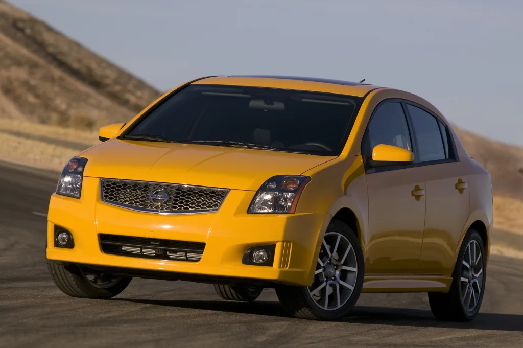 Nissan Sentra SE-R Spec V amarelo de frente no asfalto com montanhas ao fundo