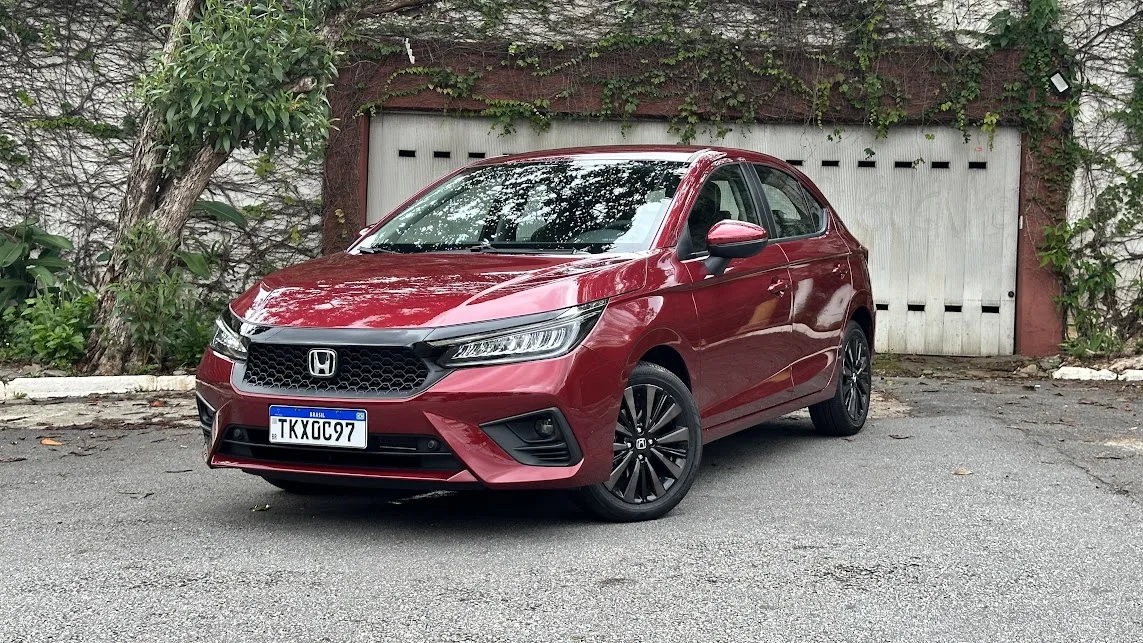 Honda City Hatch Touring 2025 vermelho estacionado em frente a um portão