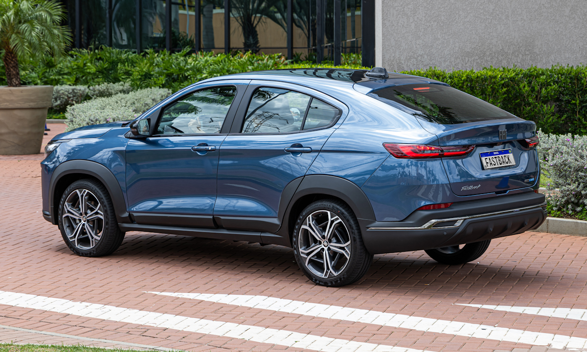 Fiat Fastback Impetus Hybrid azul Amalfi com teto preto parado de frente em um estacionamento com piso vermelho