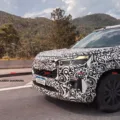 Protótipo do Honda WR-V com camuflagem branca, faróis acesos, visto de frente e com montanha ao lado