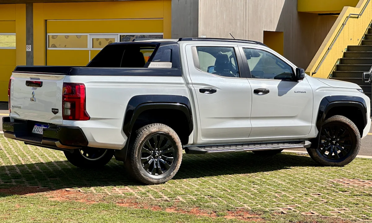 Mitsubishi Triton Katana branca estacionada em um gramado de traseira com detalhes pretos