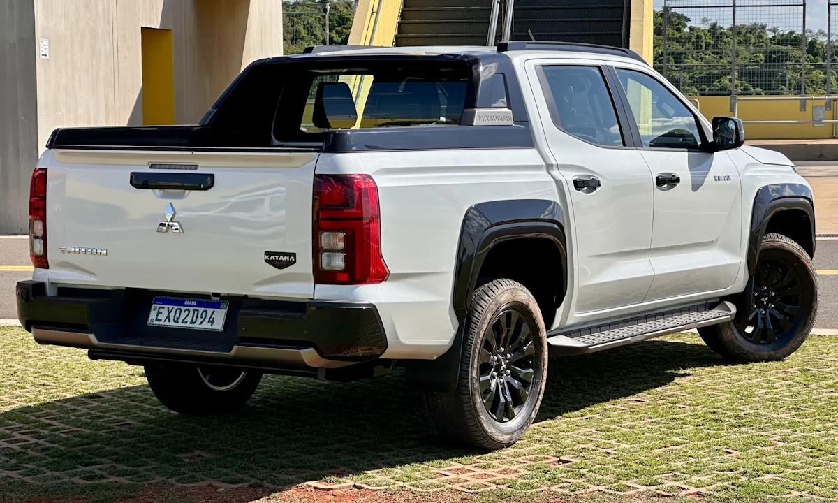 Mitsubishi Triton Katana branca estacionada em um gramado de traseira com detalhes pretos