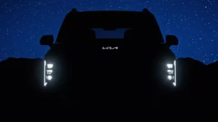 Teaser do Kia Syrons com os faróis e logo da Kia iluminados com fundo azul