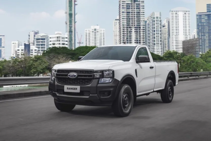 Ford Ranger com duas portas andando na cidade sobre o asfalto com prédios ao fundo