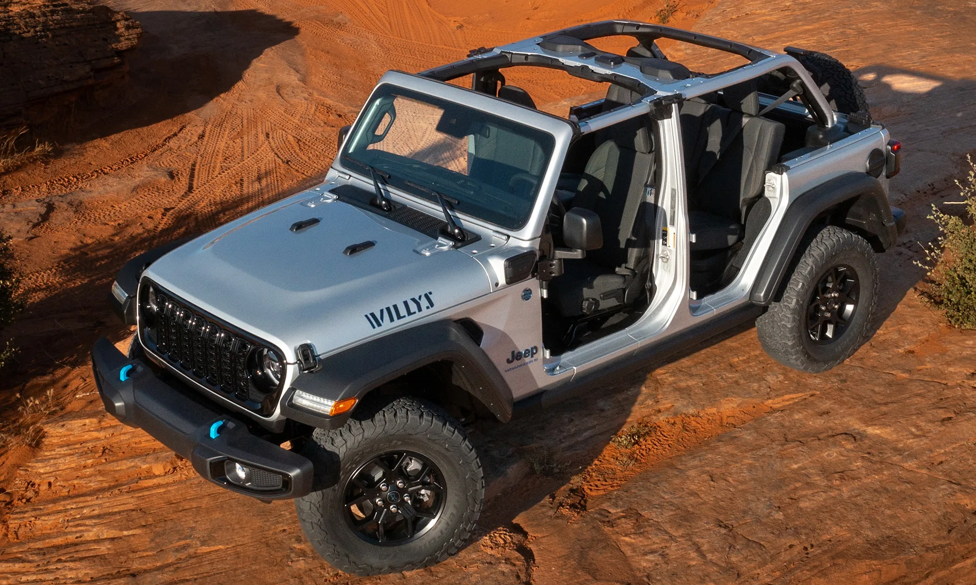 Jeep Wrangler Willys 4xe prata com detlahes em preto parado no alto da montanha