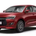 Maruti Suzuki Dzire vermelho, visto de frente e com fundo branco