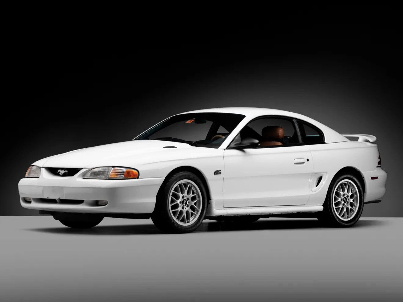 Ford Mustang branco de frente com chão e fundo cinza