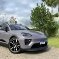 Porsche Macan 4 roxo parado de frente com árvore e casa ao fundo