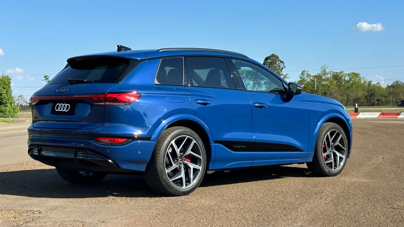 Audi Q6 e-tron azul parado de traseira no asfalto com árvores ao fundo