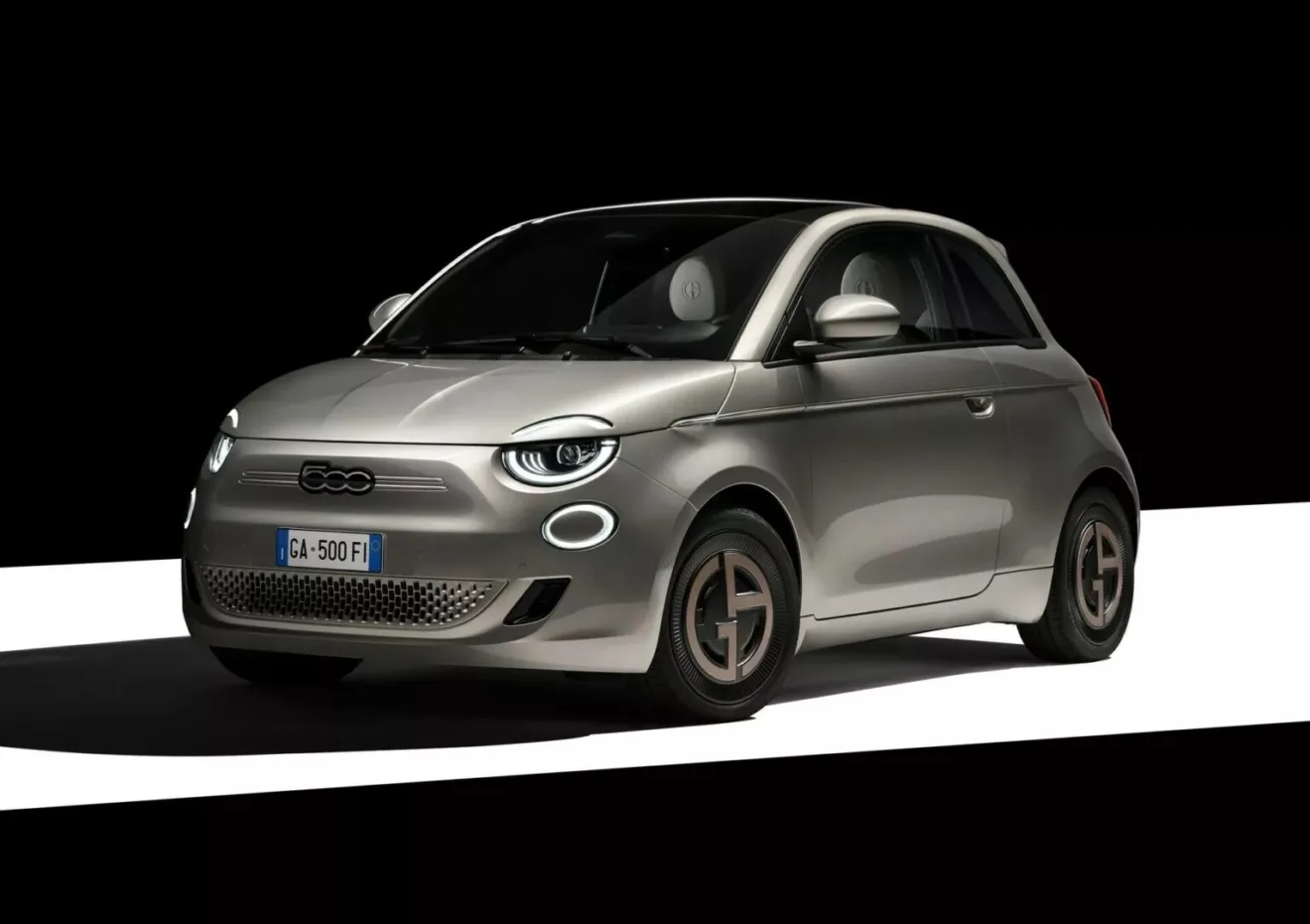 Fiat 500e Giorgio Armani bege, visto de frente e com fundo escurecido