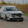 Protótipo do novo Audi Q7 com camuflagem preta e branca e visto de frente com fundo claro