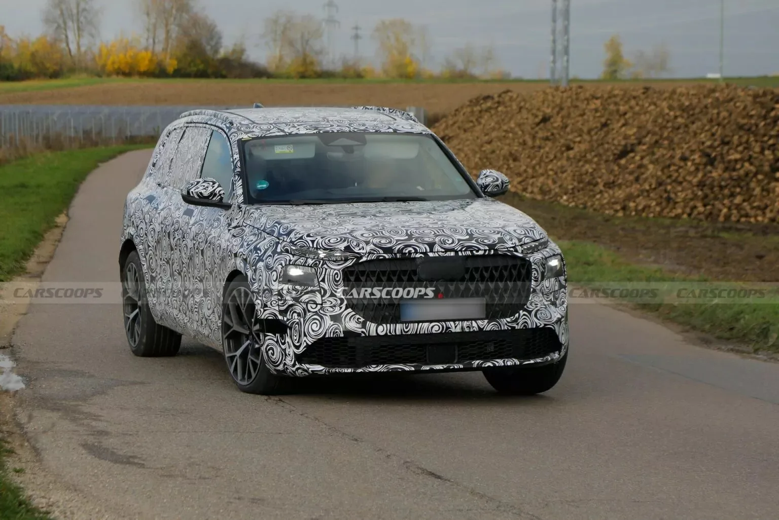 Protótipo do novo Audi Q7 com camuflagem preta e branca e visto de frente com fundo claro