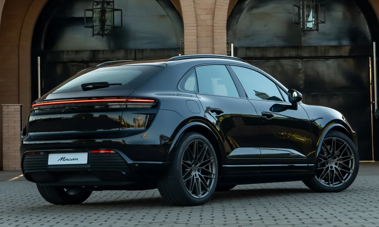 Traseira do novo Porsche Macan elétrico Turbo preto com portões escurecidos ao fundo