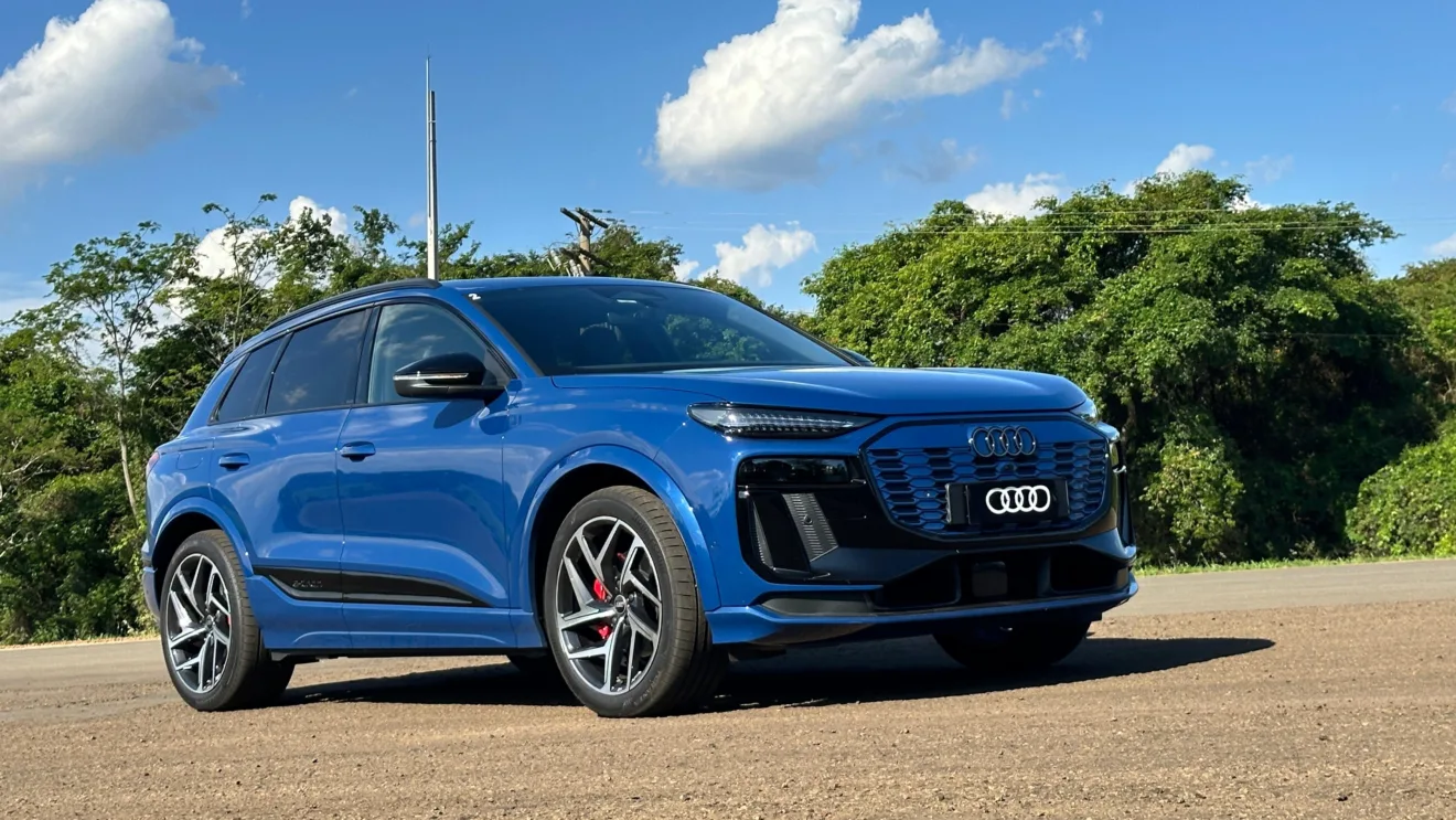 Audi Q6 e-tron azul parado de frente no asfalto com árvores ao fundo