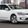 Volkswagen e-Golf branco, visto de frente e com prédios ao fundo