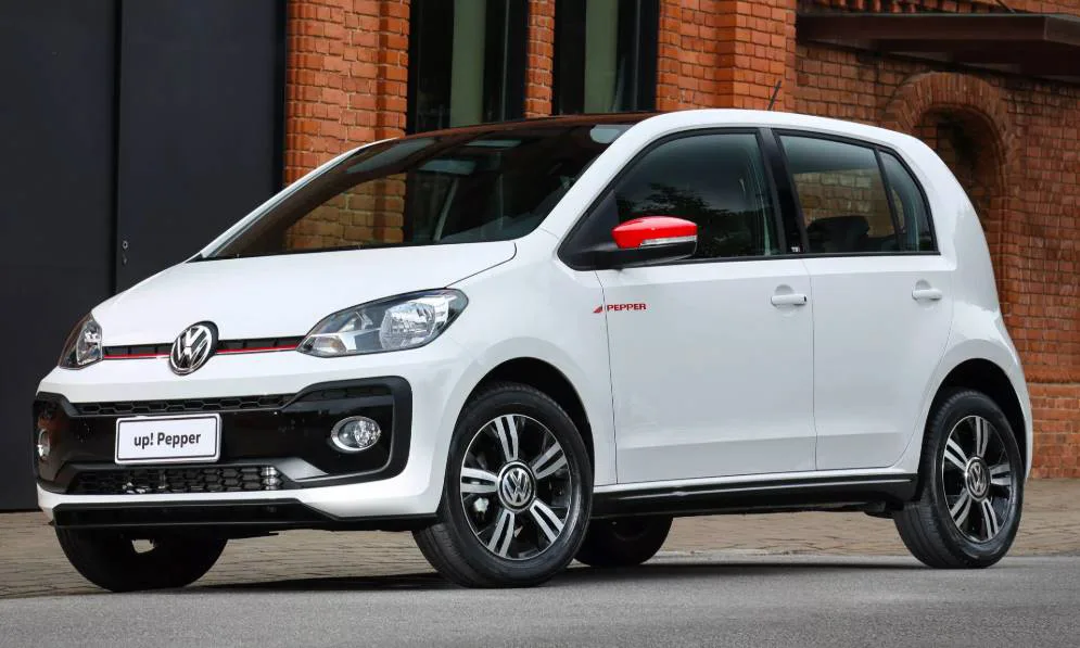 Voklswagen Up! Pepper branco parado de frente com prédio de tijolos ao fundo