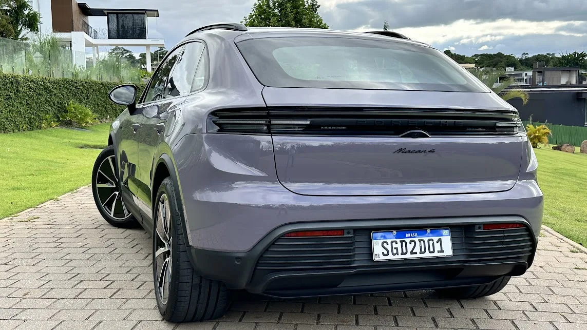 Porsche Macan 4 roxo parado de traseira com árvore e casa ao fundo