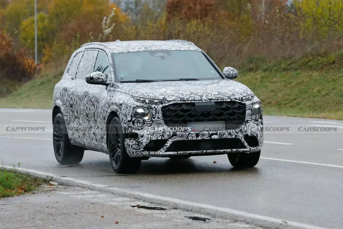 Protótipo do novo Audi SQ7, visto de frente, com camuflagem preta e branca e árvores atrás