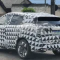 Novo Nissan Kicks camuflado de preto e branco, visto de trás e casas ao redor