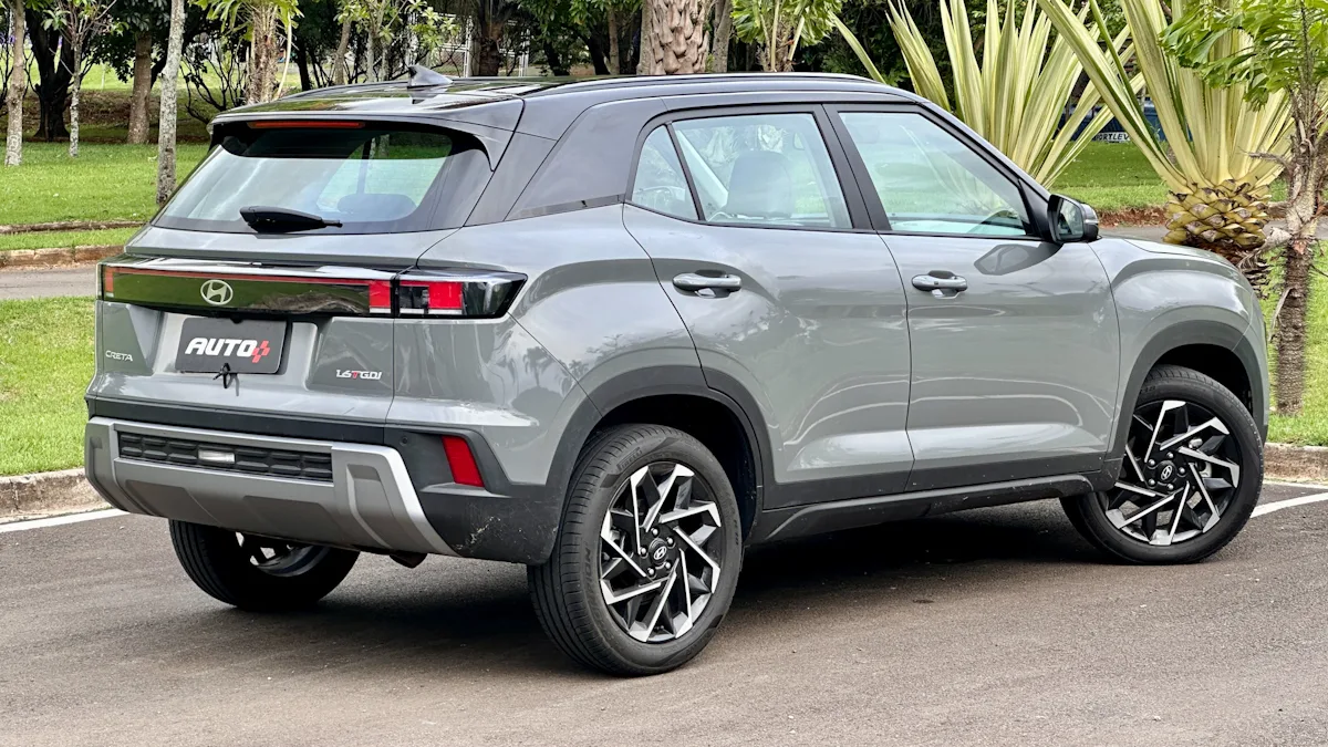 Hyundai Creta Ultimate cinza com teto preto estacionado de traseira mostrando a frente com um jardim ao fundo