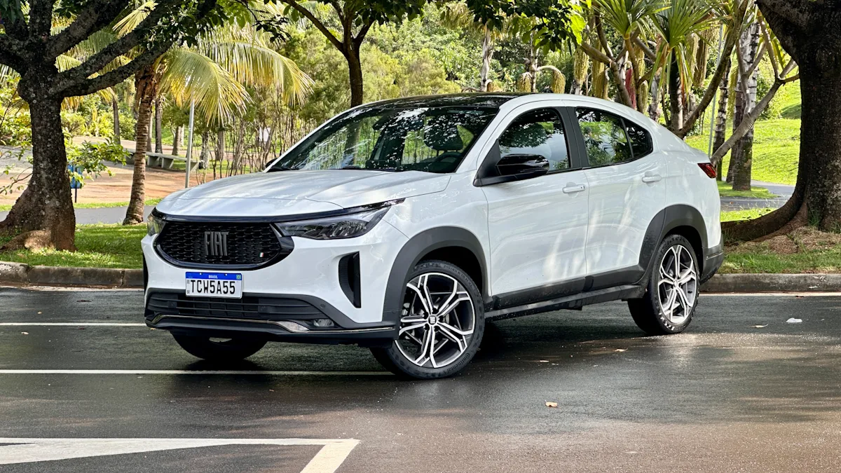 Fiat Fastback Hybrid branco de traseira em um estacionamento molhado com uma floresta ao fundo