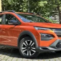 Renault Kardian Evolution MT laranja parado de frente com muro e árvore ao fundo