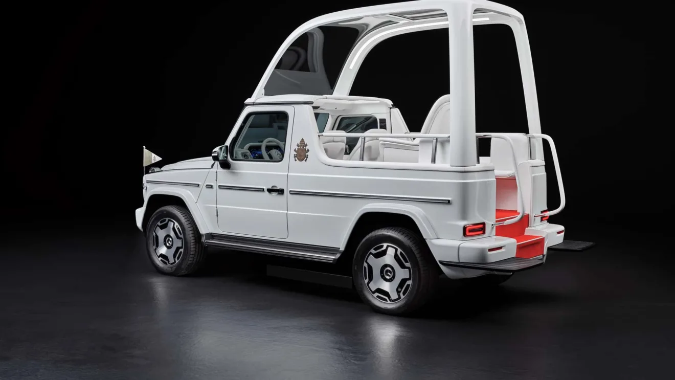 Mercedes-Benz Classe G elétrico branco como Papamóvel, com faróis acesos e bandeirinhas amarelas, visto de trás com teto removível