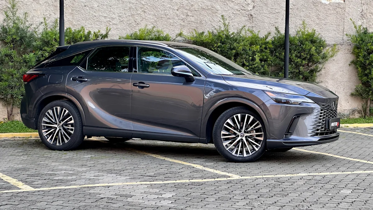 Lexus RX450h cinza de lado em um estacionamento com um muro de plantas atrás