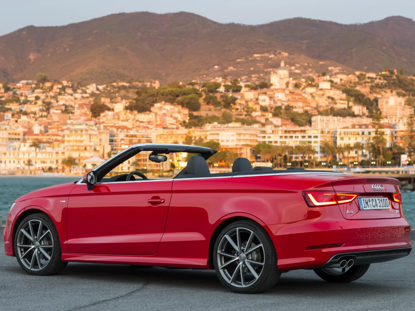 Audi A3 Conversível vermelho parado de traseira com mar e prédios ao fundo é outra opção de conversíveis à venda no Brasil 