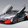 BMW Vision M Next prata com parte alaranjada, visto de frente, com portas abertas e fundo claro