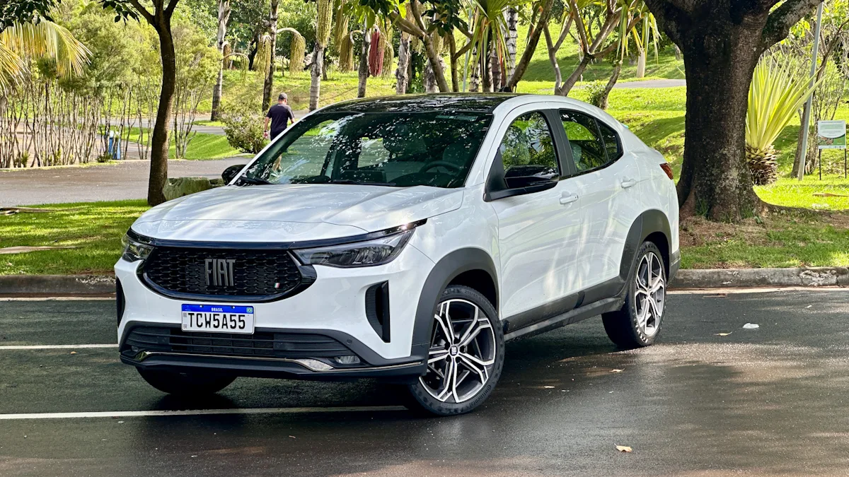 Fiat Fastback Hybrid branco em um estacionamento molhado com uma floresta ao fundo