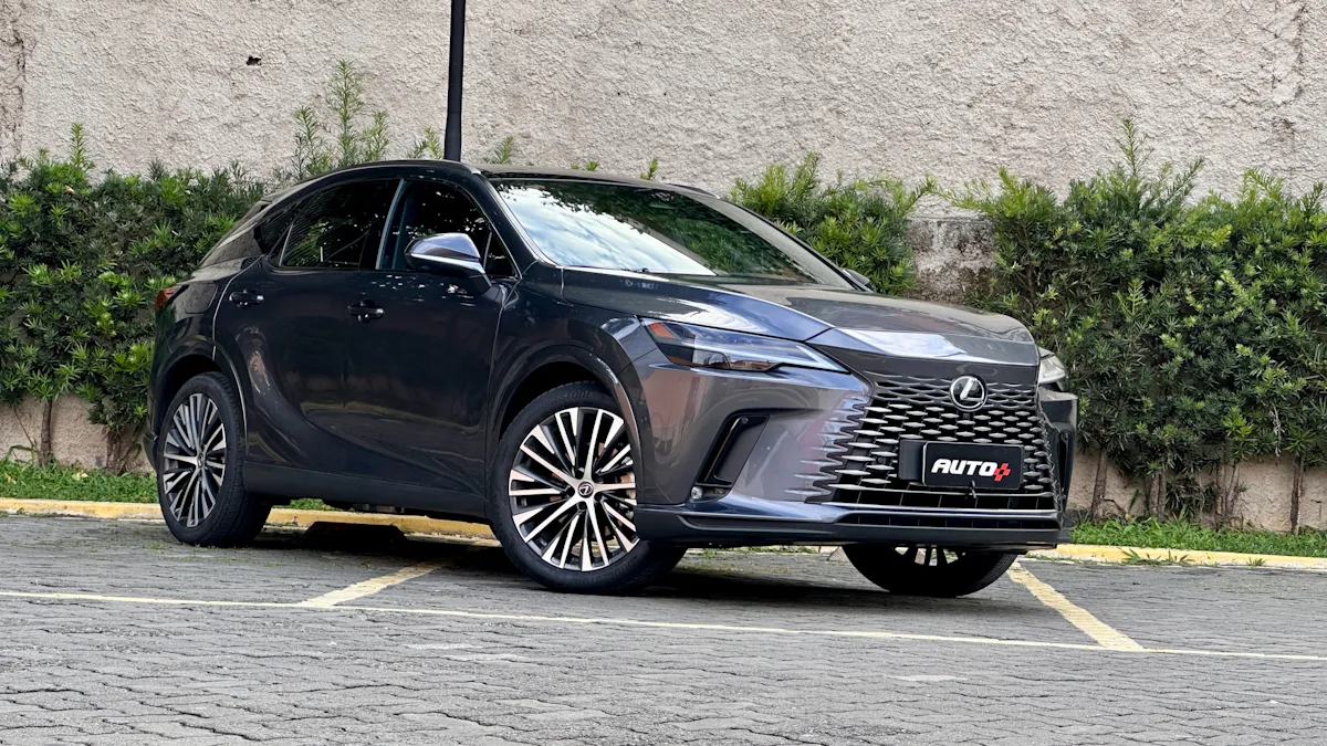 Lexus RX450h cinza de frente em um estacionamento com um muro de plantas atrás