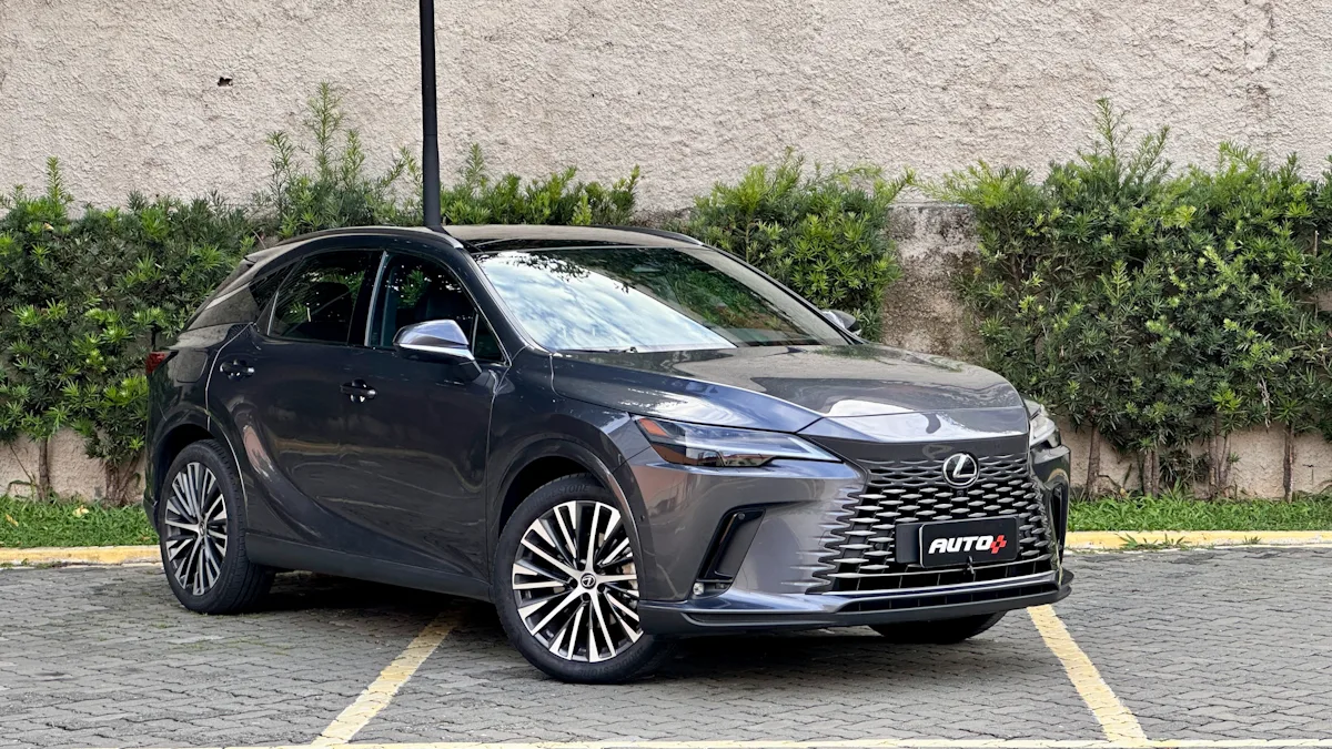 Lexus RX450h cinza de frente em um estacionamento com um muro de plantas atrás