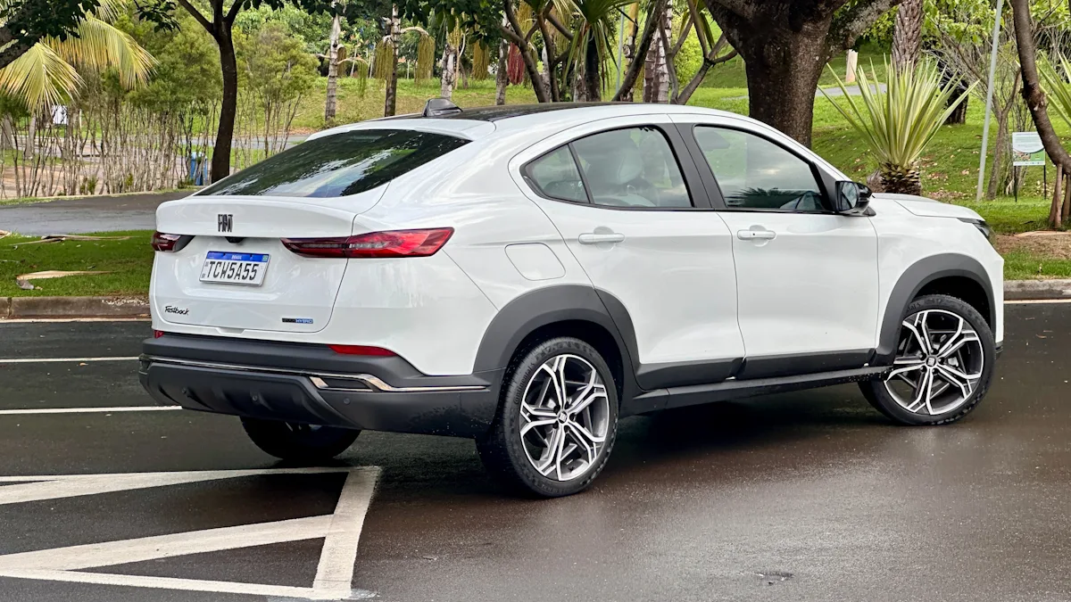 Fiat Fastback Hybrid branco em um estacionamento molhado com uma floresta ao fundo